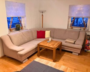 Una sala de estar con un sofá seccional color beige, una mesa de centro de madera y una lámpara de pie.