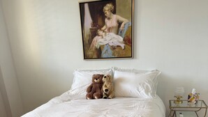 A bedroom with a large bed, a bedside table with a lamp, and a painting on the wall. - Beautiful Renovated South Beach Condo on Lincoln Road withParking and Balcony (Miami Beach)