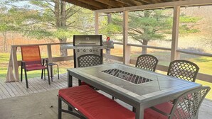 Une terrasse extérieure avec un barbecue, une table et des chaises.