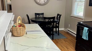 Une cuisine dotée d’un plan de travail en marbre, d’une table à manger avec des chaises, d’un ventilateur de plafond et d’une horloge murale.