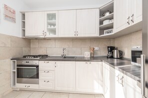 A modern kitchen with white cabinets, a stainless steel stove, and a built-in oven. - Privlaka Villa Near the Adriatic Sea (Privlaka)