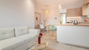 Una cocina moderna con una isla central, armarios blancos y un comedor con mesa y sillas.