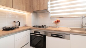 Una cocina moderna con armarios de madera, estufa a gas, horno y lavavajillas.