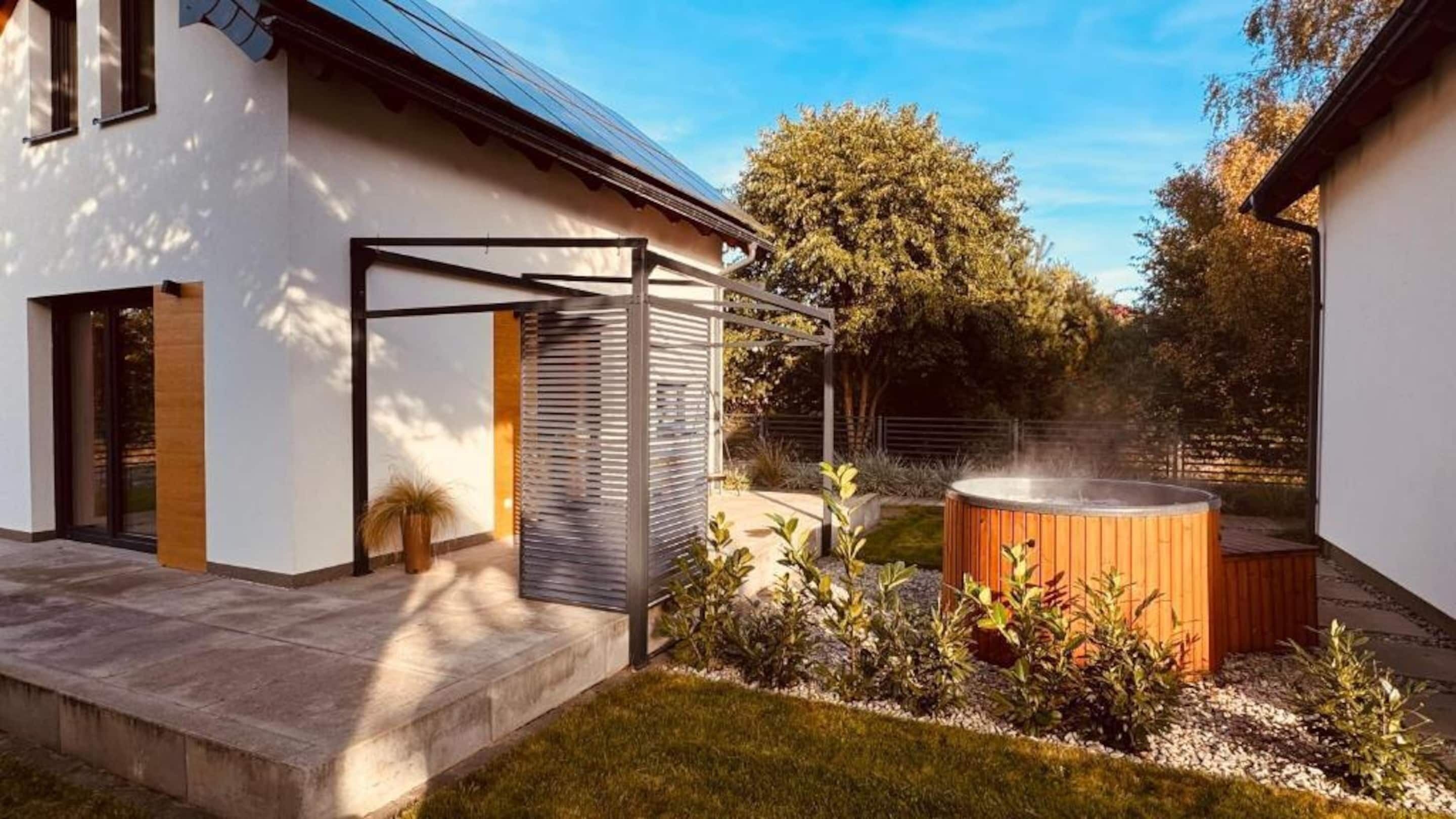 A modern house with a patio, a hot tub, and a garden.