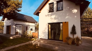 A modern two-story house with a large glass door and a small tree in the front yard. - Holiday Home, Sea, Jacuzzi, for 4 People (Wladyslawowo)