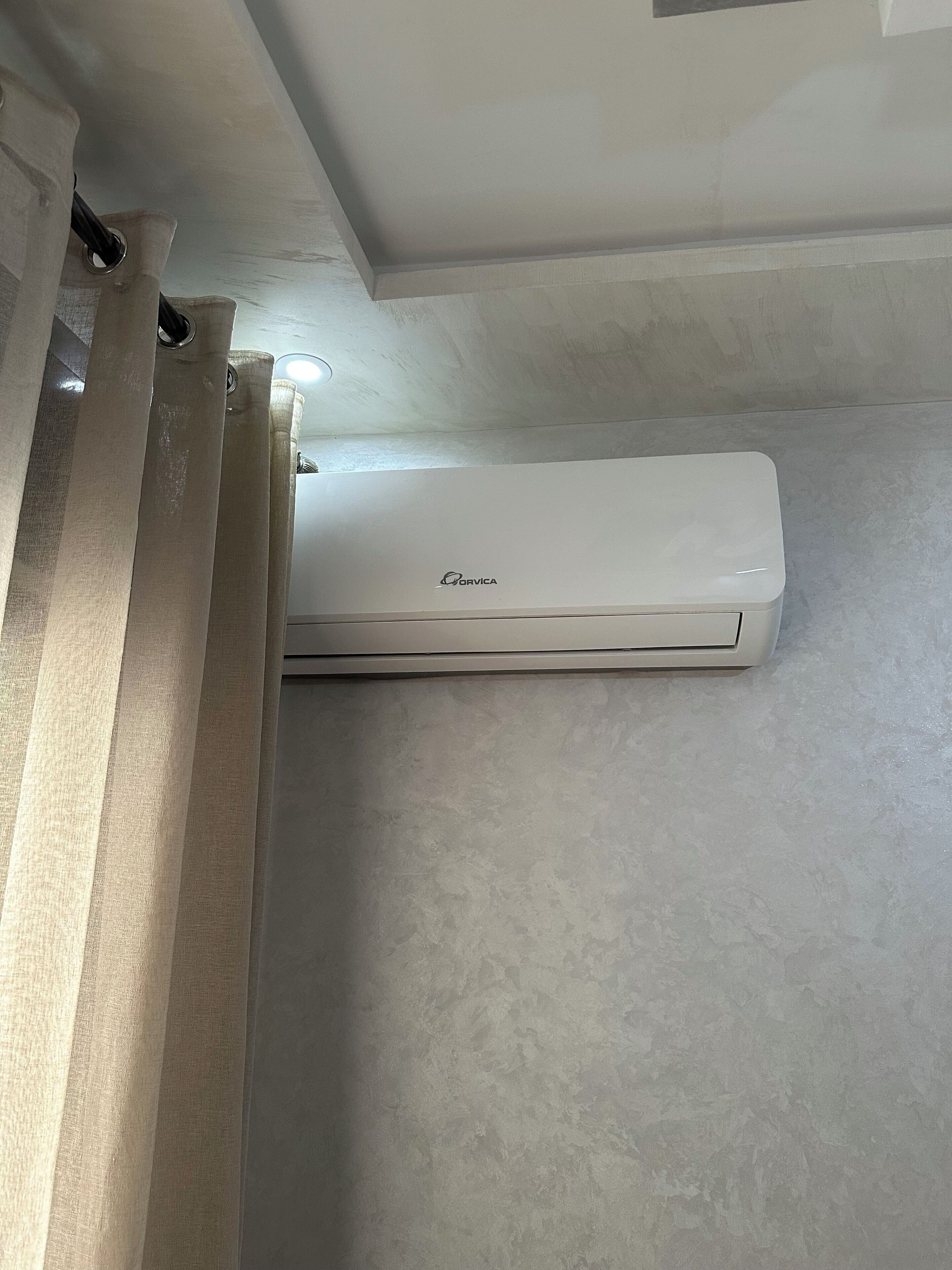 Eine weiße Klimaanlage an einer strukturierten Wand angebracht.