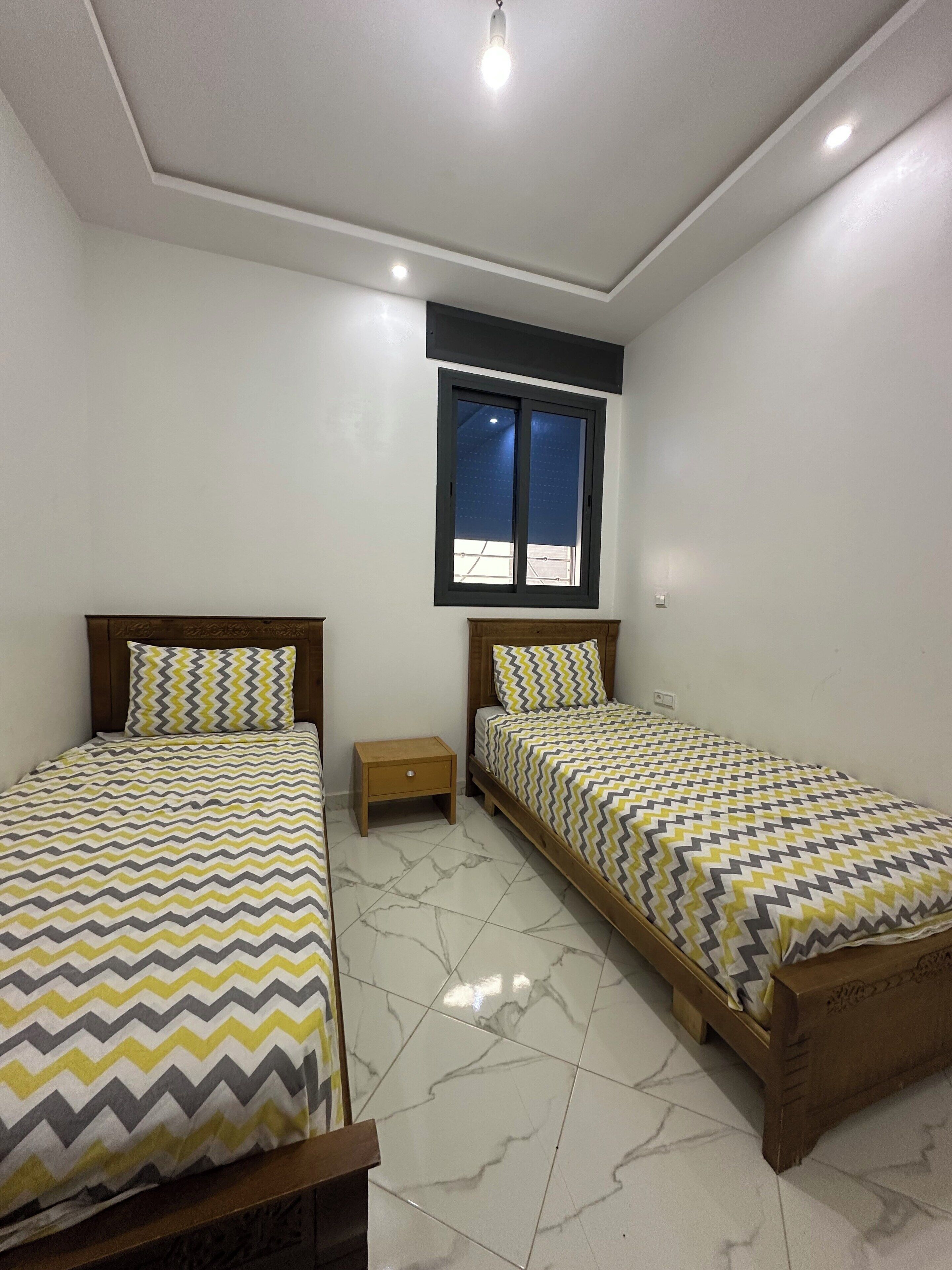 Una camera da letto con due letti, una finestra e un comodino.