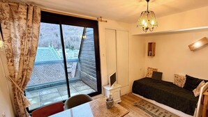 Una habitación pequeña y acogedora con una cama, un escritorio y una ventana que da a un edificio.