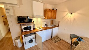 Una cocina compacta equipada con microondas, cafetera y armarios de madera.