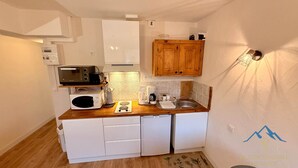 Una cocina compacta con armarios blancos, microondas, cafetera y encimera de madera.