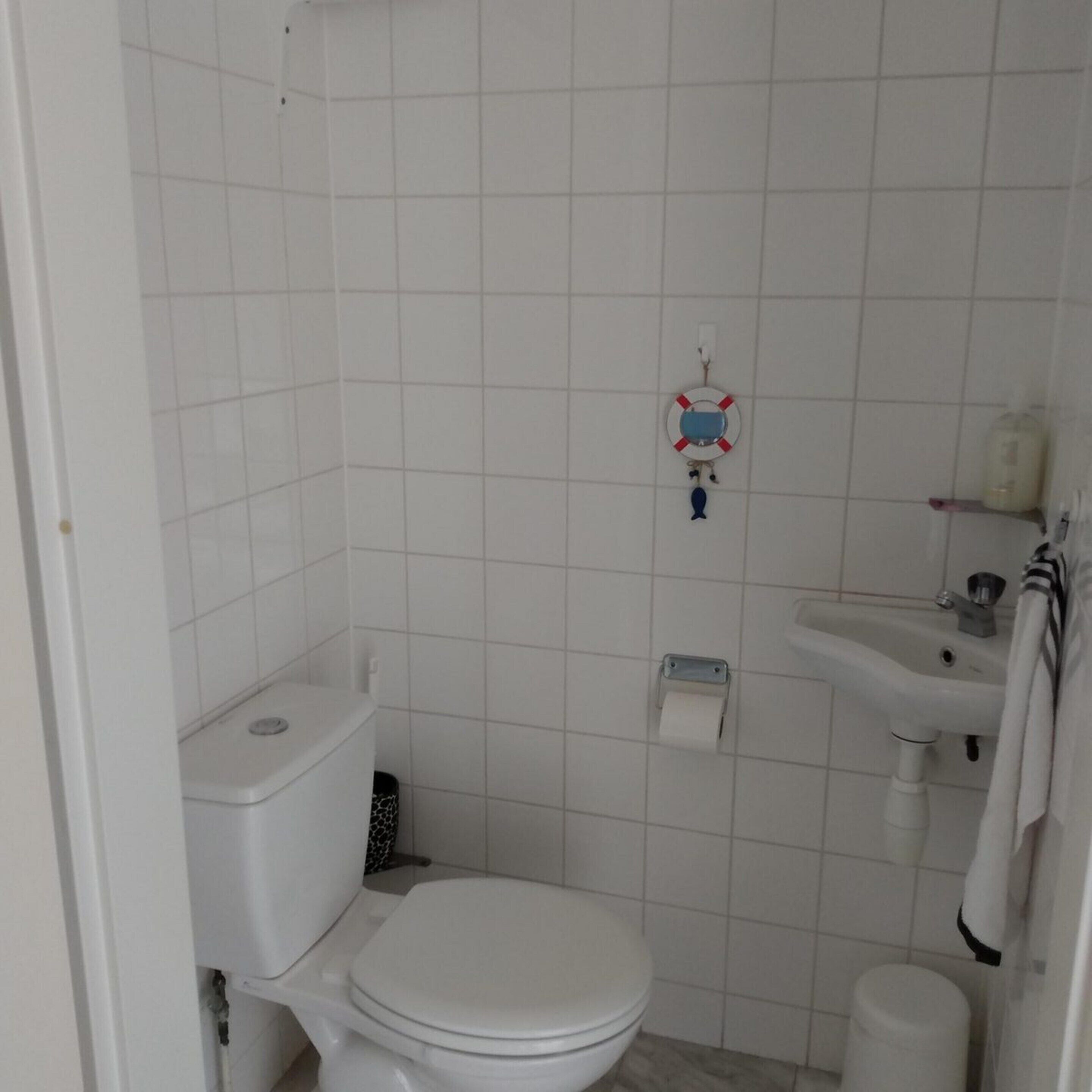 A small, clean bathroom with a toilet, sink, and a toilet paper holder.