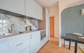 A modern kitchen with a marble backsplash, stainless steel appliances, and light-colored cabinetry. - PARIS - Adorable 3-room apartment with 2 bedrooms and 2 bathrooms (Bagnolet)
