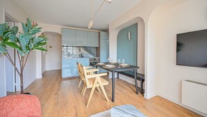 A modern kitchen with light blue cabinets, a marble backsplash, and a dining area with a round table and wooden chairs. - PARIS - Adorable 3-room apartment with 2 bedrooms and 2 bathrooms (Bagnolet)