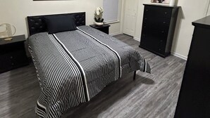 Un dormitorio con cama, televisor, cómoda y una puerta.