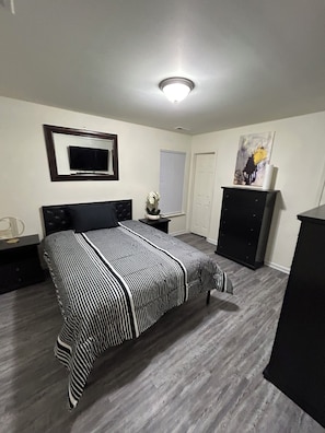A bedroom with a bed, a TV, a dresser, and a door. - Relaxing Stay in Friendly Home (Charlotte)
