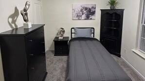 Un dormitorio con cama, cómoda, mesita de noche y un cuadro en la pared.