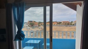 A room with a view of a sandy area and buildings in the distance. - Holiday Properties Soleil (Santa Maria)