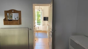 A bedroom with a bed, a dresser, a radiator, a mirror, and a door leading to a balcony. - Cozy French Alpine Retreat for 2 (Mont-Dore)