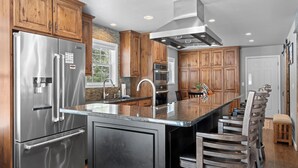 Una cocina moderna con armarios de madera, electrodomésticos de acero inoxidable y una isla grande con taburetes de bar.