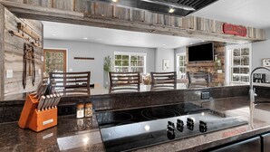 Una cocina moderna con encimera de piedra, estufa empotrada y detalles de madera.