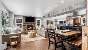 Amplia sala de estar con chimenea, una mesa de comedor y una zona de cocina con armarios de madera.