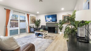 Una sala de estar con chimenea, televisor de pantalla plana en la pared, sofá y mesa de centro.