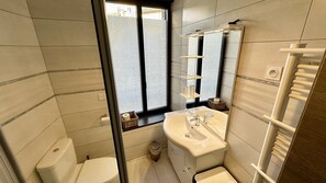 A modern bathroom with a toilet, sink, and mirror. There is a window with a view of the outside. - Au Coeur du Mont Dore : 6 Personnes (Mont-Dore)