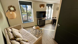 En moderne stue med sofa, fjernsyn og spiseplads.
