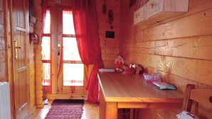 A cozy wooden cabin interior with a wooden table, red curtains, and a red carpet. - Roulotte La passe pierre En baie de Somme (Pendé)
