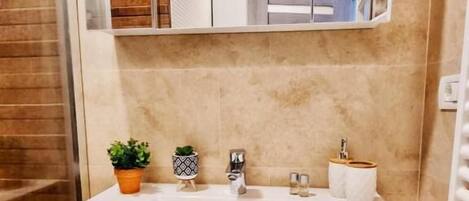 A bathroom with a white sink, two faucets, a mirror above the sink, and a wooden floor.