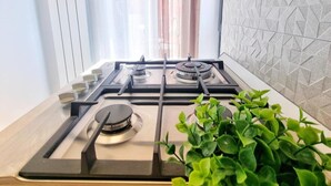 Una cocina moderna con estufa a gas, campana extractora y una planta en maceta.