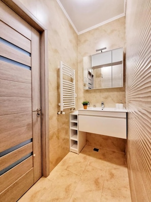Ein Badezimmer mit Holztür, Waschbecken, Spiegel und Handtuchhalter.