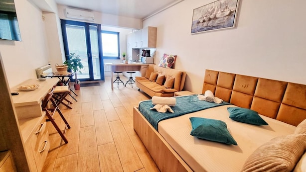 Un apartamento moderno con una cama grande, un sofá, una zona de comedor y una cocina.