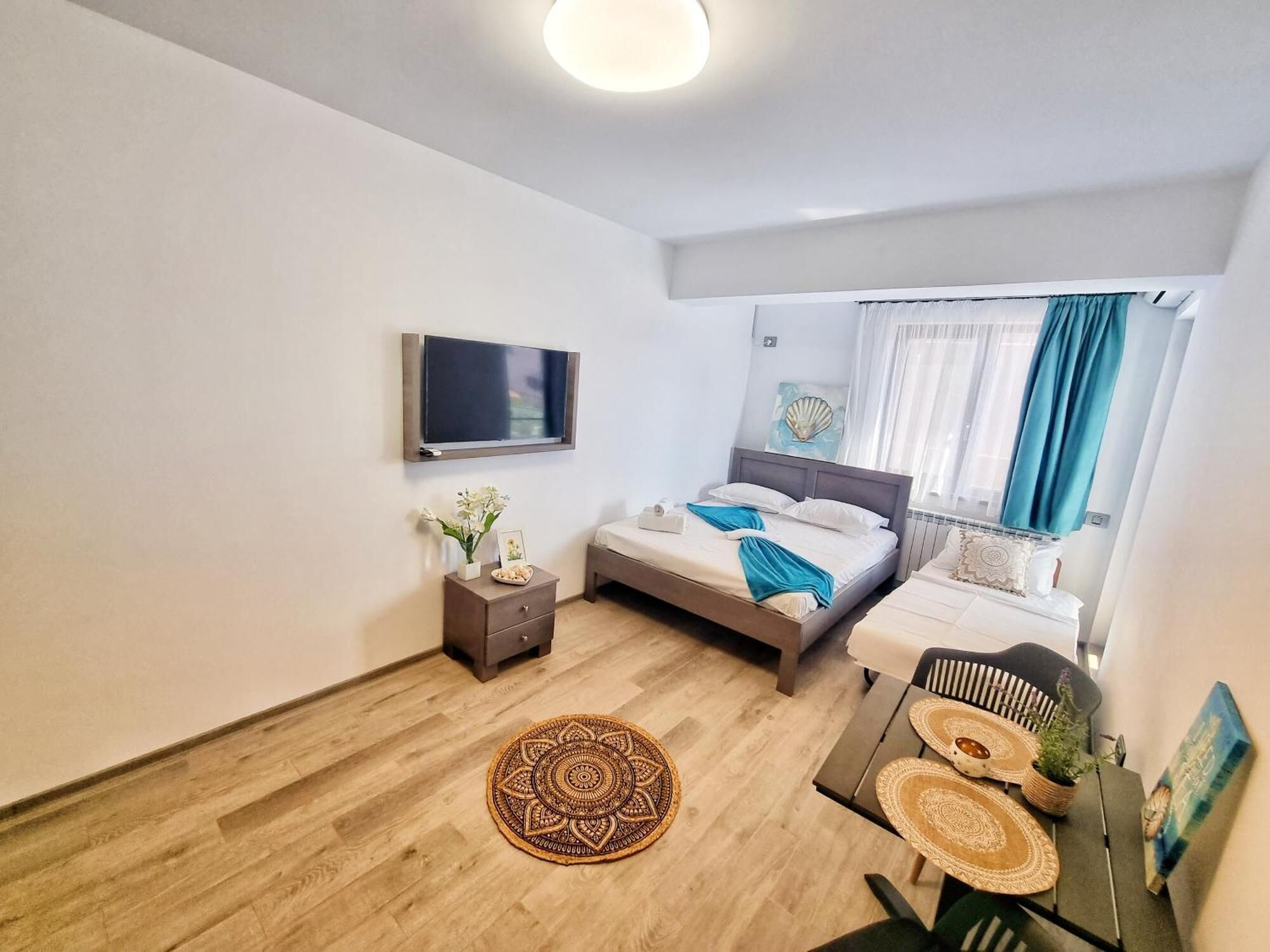 Un dormitorio moderno con cama, mesita de noche, televisor y vistas al exterior.