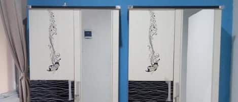 A room with two white wardrobes against a blue wall, each with a decorative design and a small mirror.