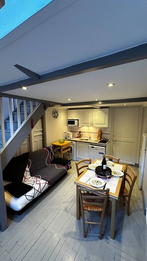 A compact living space with a dining area, kitchenette, and a sofa bed. - Charming Mont-dore Duplex Stay (Mont-Dore)