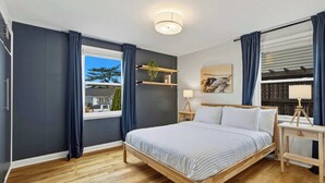 Une chambre moderne avec un lit en bois, des murs sombres et une grande fenêtre avec des rideaux.