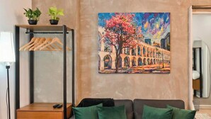 Uma sala de estar moderna com um sofá, uma mesa de centro e um quadro de uma cena urbana.
