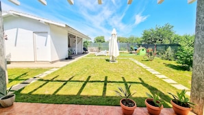A covered patio area with a lawn, potted plants, and a playhouse. - Casa Cochilia-Camere de inchiriat (Eforie Nord)