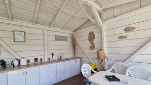 A kitchen with white cabinets, a wooden countertop, and a hanging net. There is a sign on the wall that says "Dream." - Casa Cochilia-Camere de inchiriat (Eforie Nord)