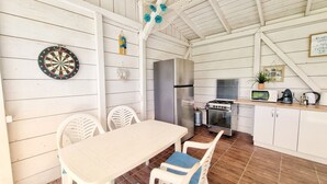 A kitchen with a dining table, chairs, a refrigerator, a stove, and a microwave. - Casa Cochilia-Camere de inchiriat (Eforie Nord)