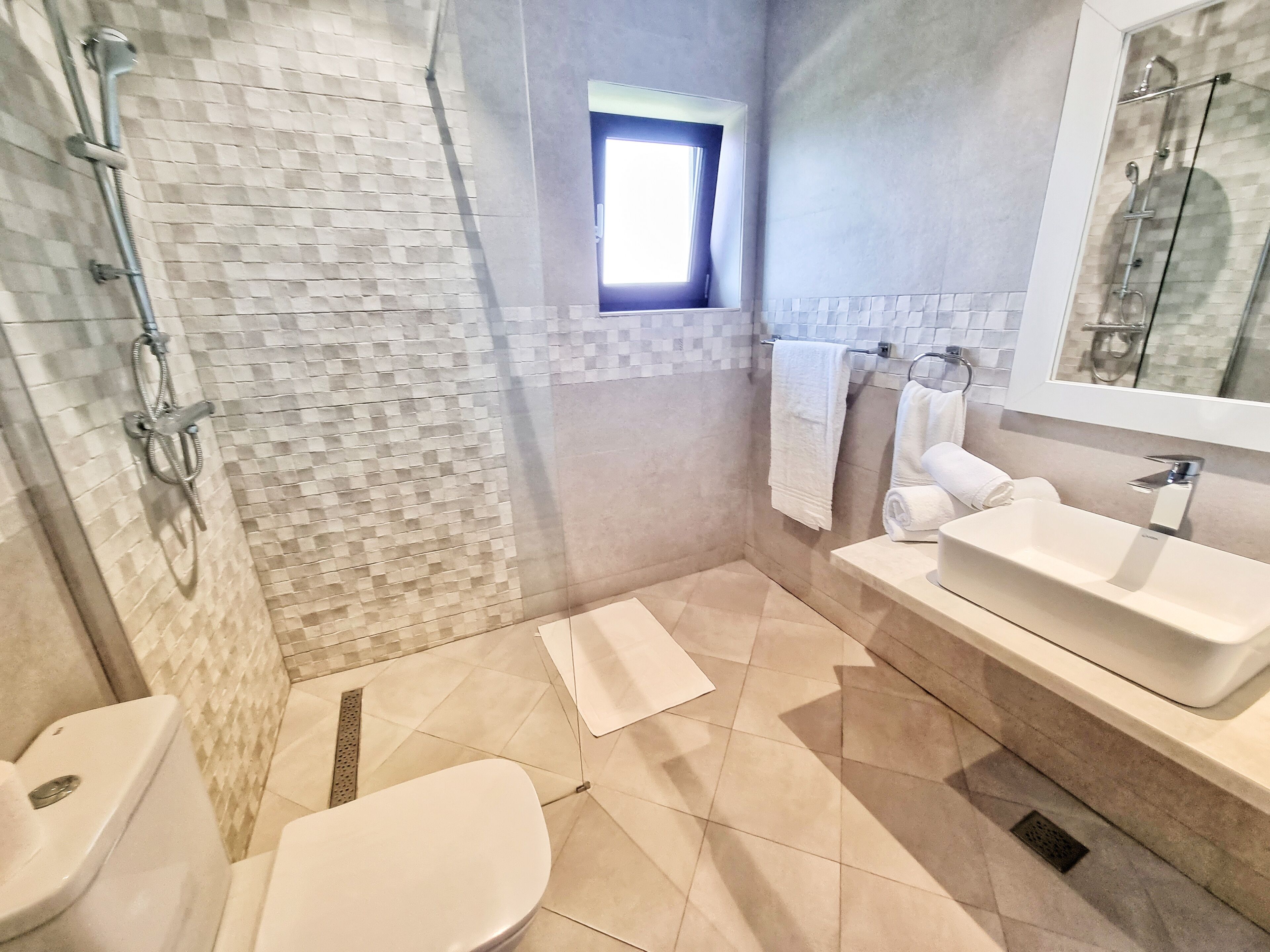 A modern bathroom with a shower, toilet, and sink.