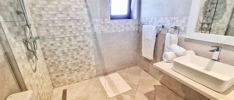 A modern bathroom with a shower, toilet, and sink.
