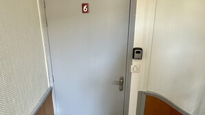 A door with a number 6 sign, a doorbell, and a doormat. - Mountain View Flat for 5 in Mont-dore (Mont-Dore)