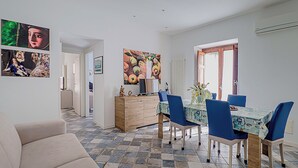 A dining area with a table, chairs, and a painting on the wall. - Angelina's apartment (Cefalù)