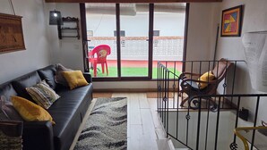 Ein Wohnzimmer mit einem schwarzen Ledersofa, einem gemusterten Teppich, einem roten Sessel und einer Holzgeländer.