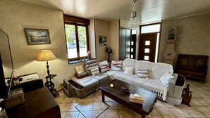 Una sala de estar con sofá, una mesa de centro, una lámpara y un ventanal con vistas al exterior.