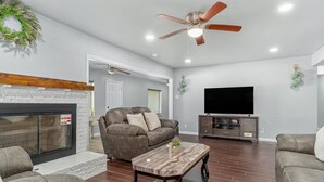 A living room with a fireplace, a sofa, a coffee table, and a TV. - Home in Dallas / Entire Home (Dallas)