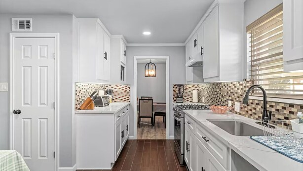 A modern kitchen with white cabinetry, a tiled backsplash, and a central island. - Home in Dallas / Entire Home (Dallas)