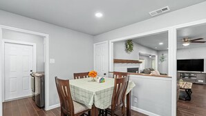 A dining area with a table set for four, a kitchen in the background, and a living area with a TV. - Home in Dallas / Entire Home (Dallas)